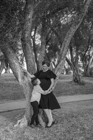 A tender black and white moment shared between two people by a large tree.