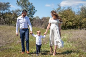 A family walks hand in hand through a sunny meadow on a beautiful spring day.