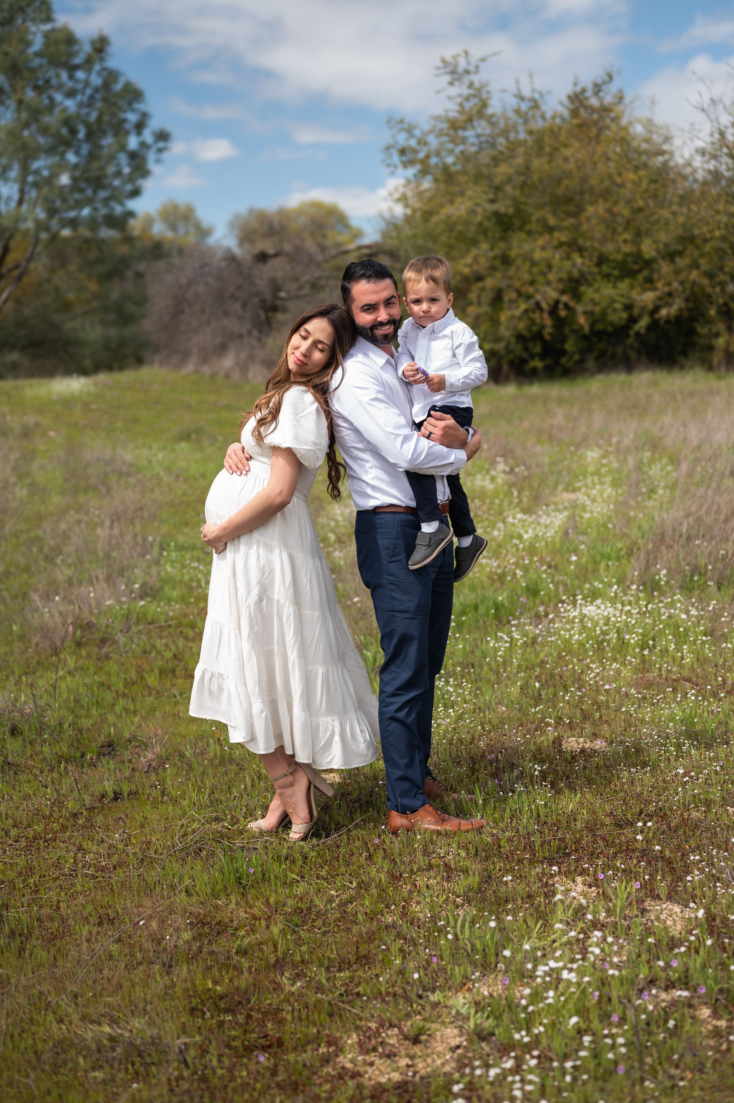 Family portrait in a wildflower meadow with white dress and navy attire.