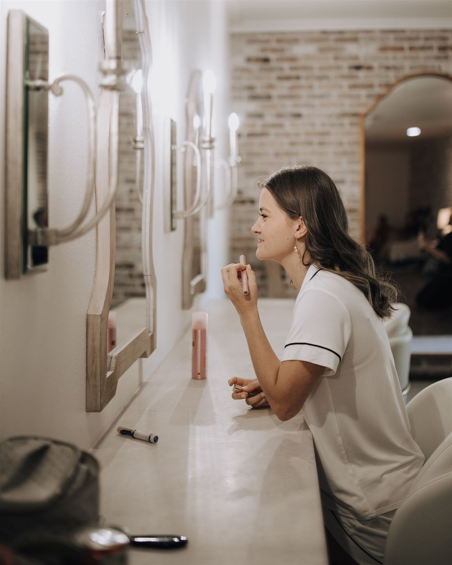 bride putting on makeup in bridal suite of Carriage House wedding venue