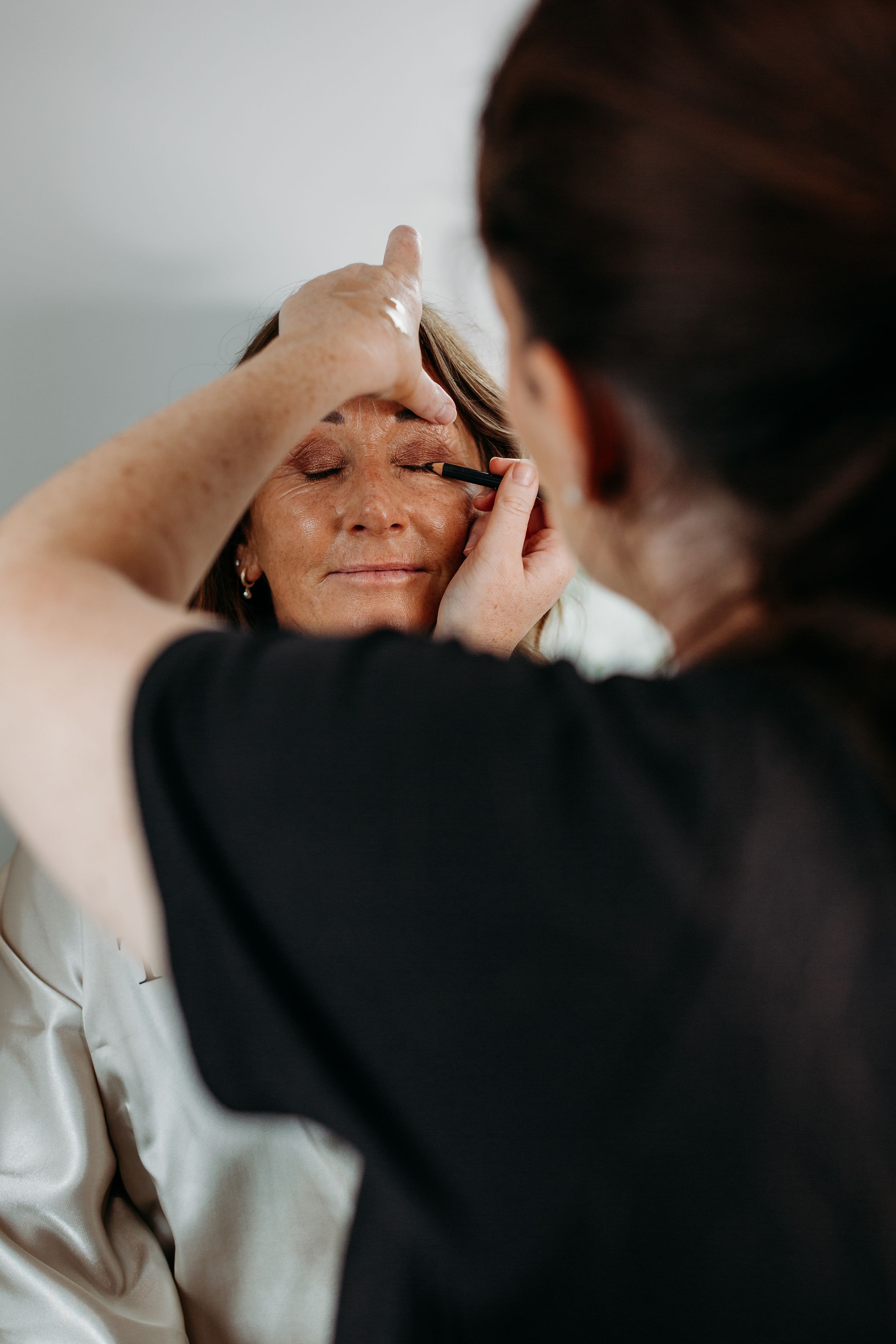 Professional makeup application in progress during wedding preparations.