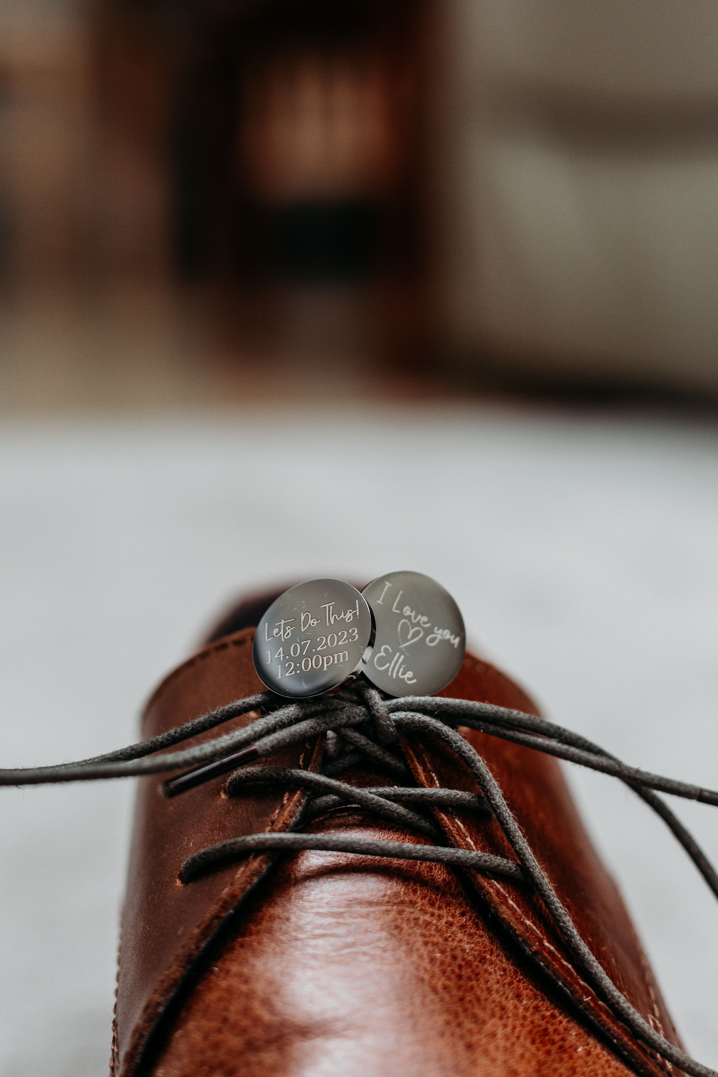 Close-up detail of engraved sixpence coins on brown leather dress shoes with laces.