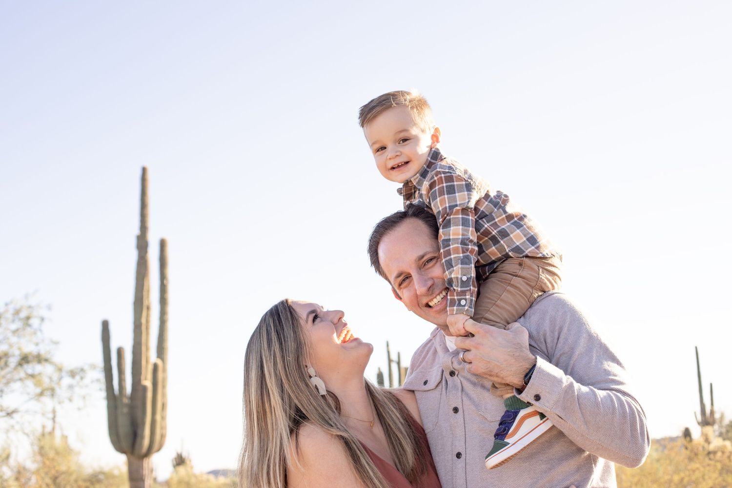 Desert family photography session featuring playful interactions against a bright sky.