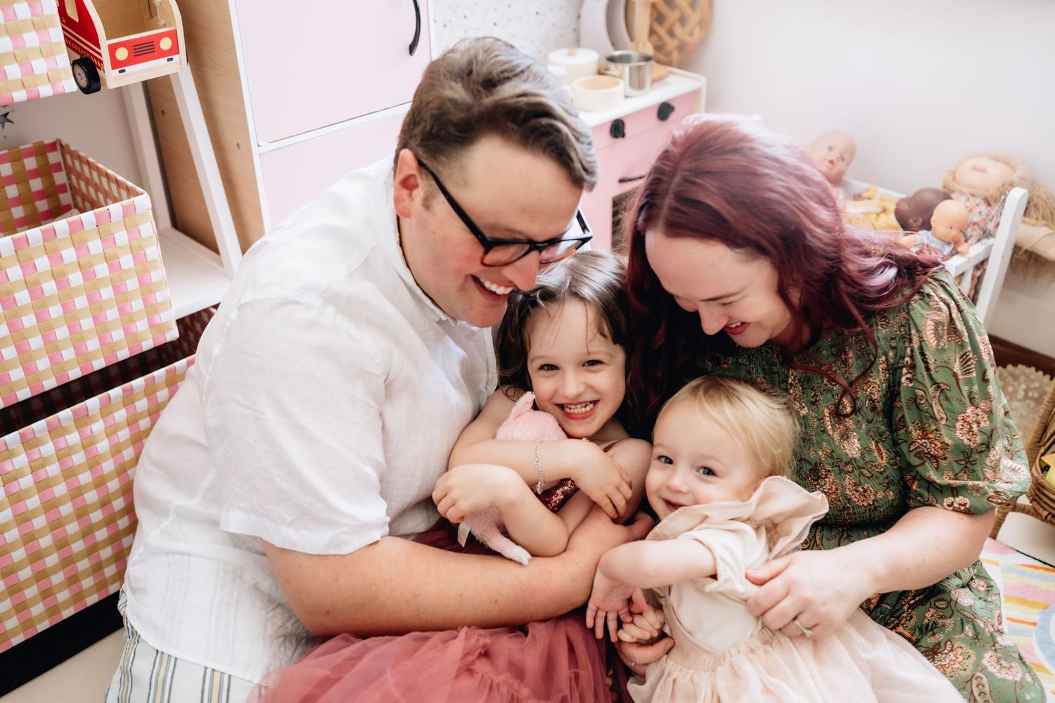 A mum, dad and two daughters cuddling in their home