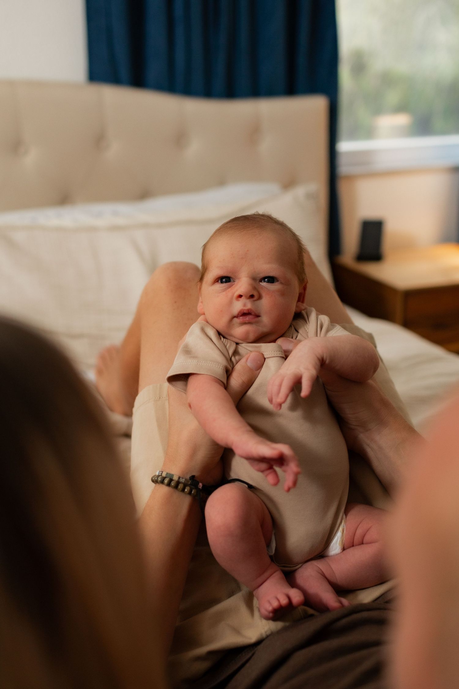 front view of newborn baby on bed with mom and dad and photo taken by heart and root photography
