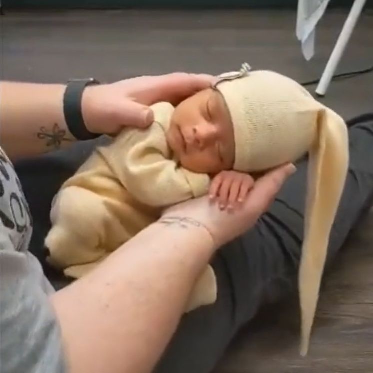 Peaceful sleeping baby wearing cream colored outfit with matching hat.