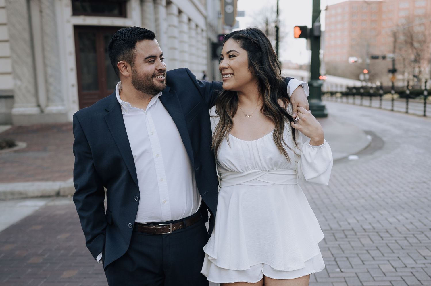 Houston area couple's engagement session. They are holding hands and walking across Franklin Street in downtown.