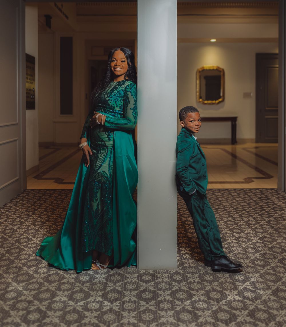 Elegant green dress photoshoot series in hallway with white columns and patterned carpet.
