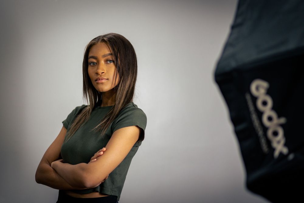 Studio portraits against a light background wearing a dark colored top.