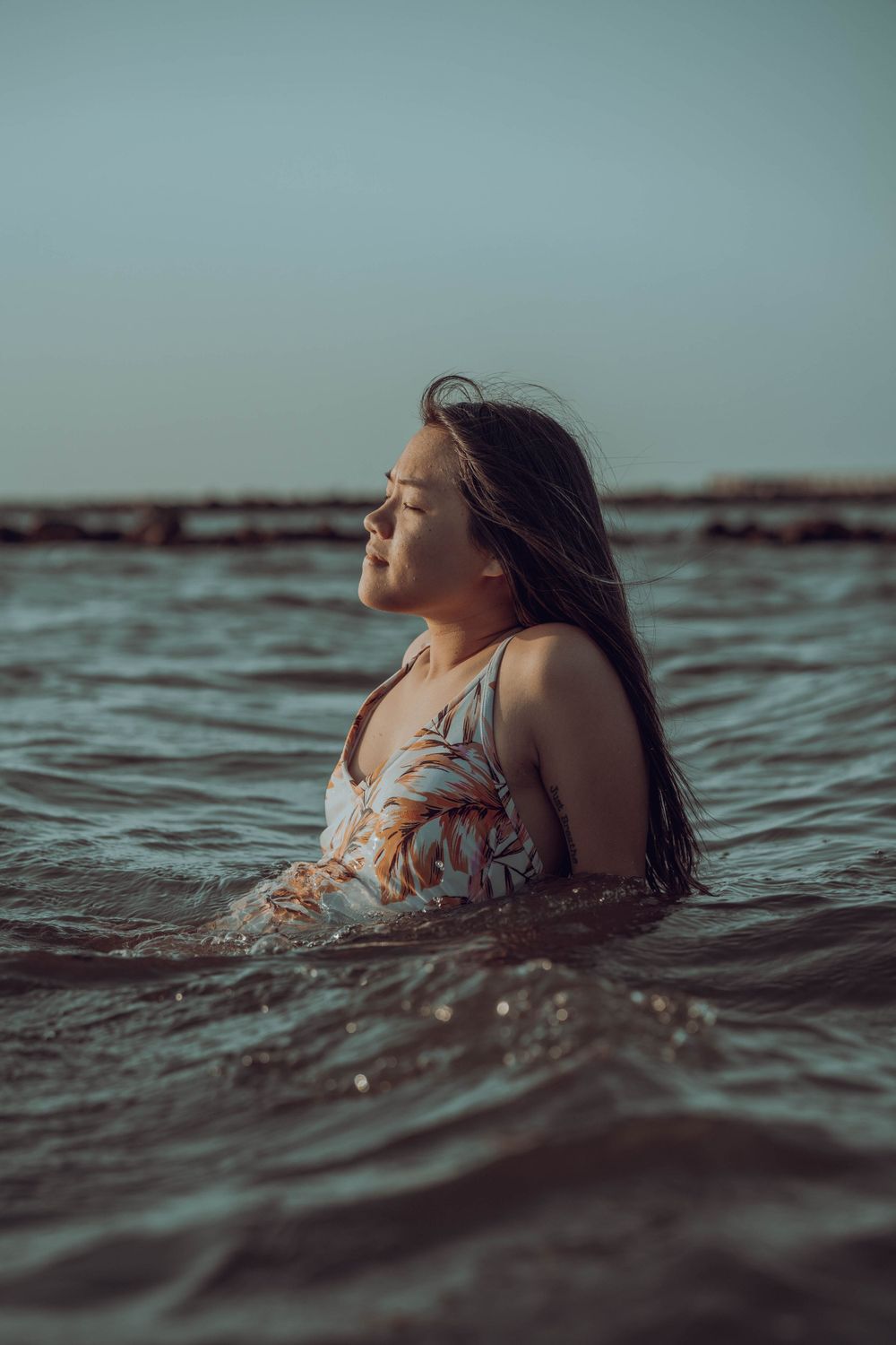 A swimmer floating peacefully in ocean waters at dusk.