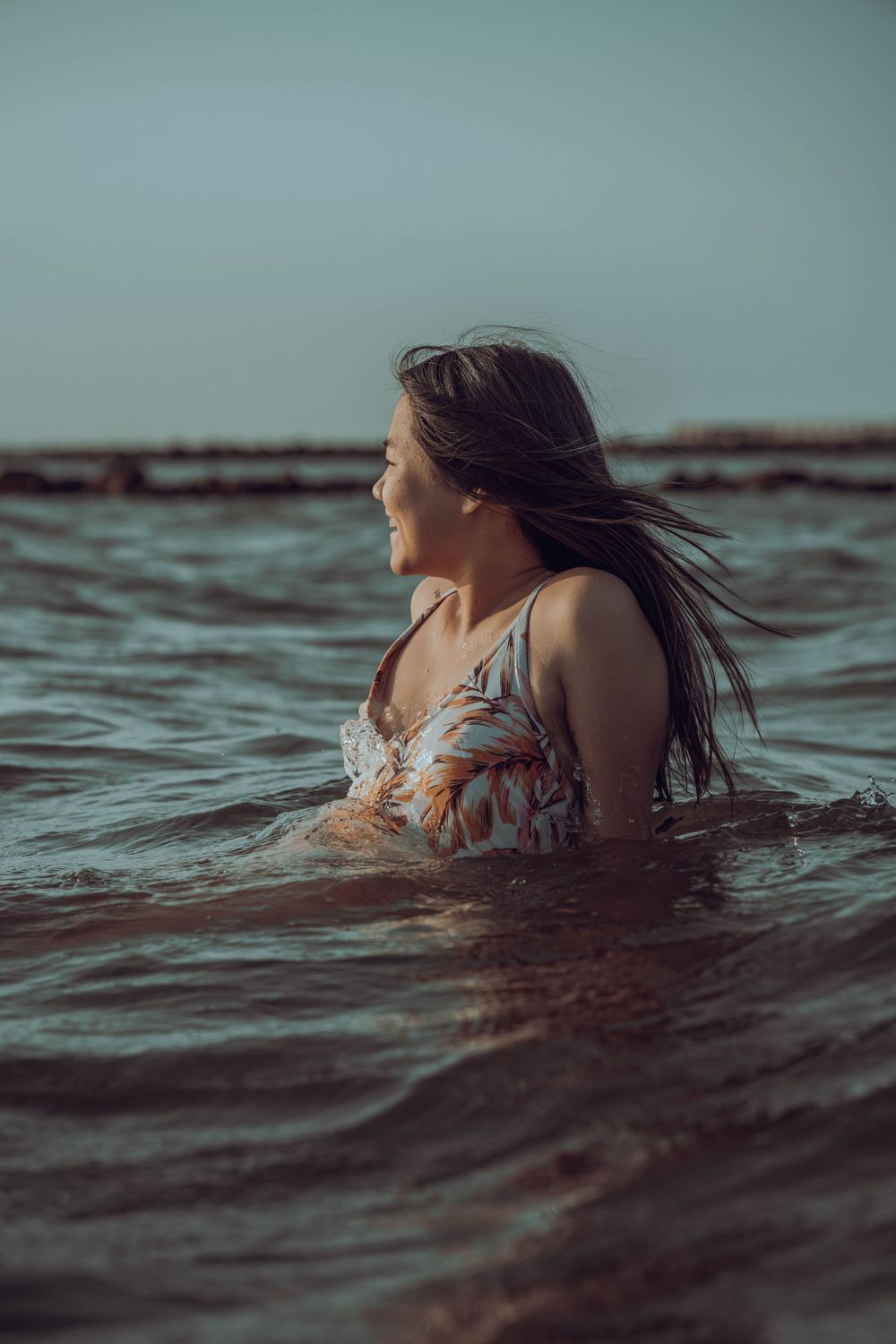 A person in floral swimwear swimming in ocean waters.