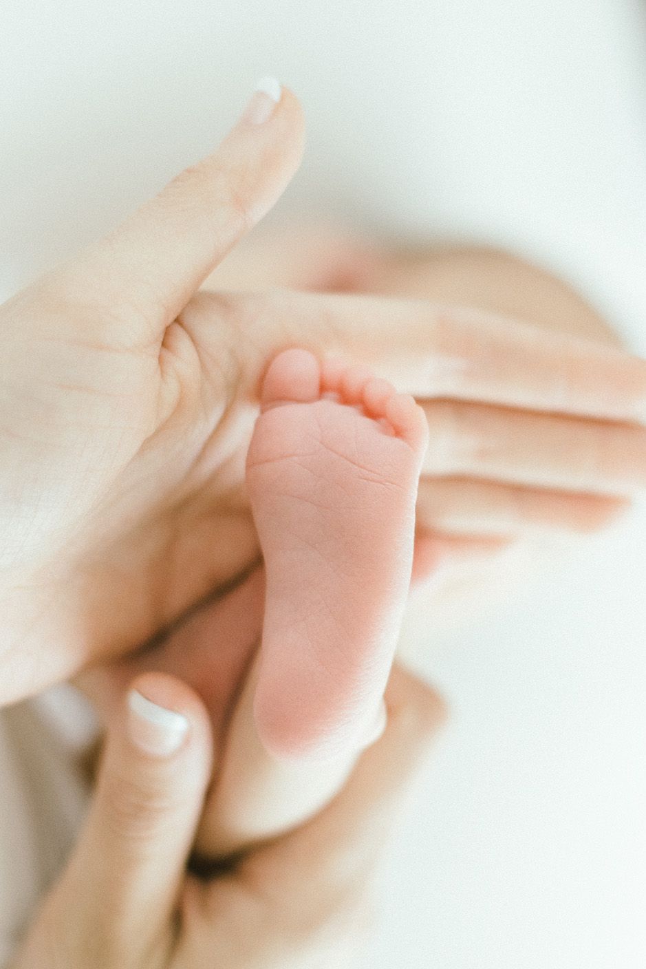 Close-up of delicate baby foot being held by caring hands.