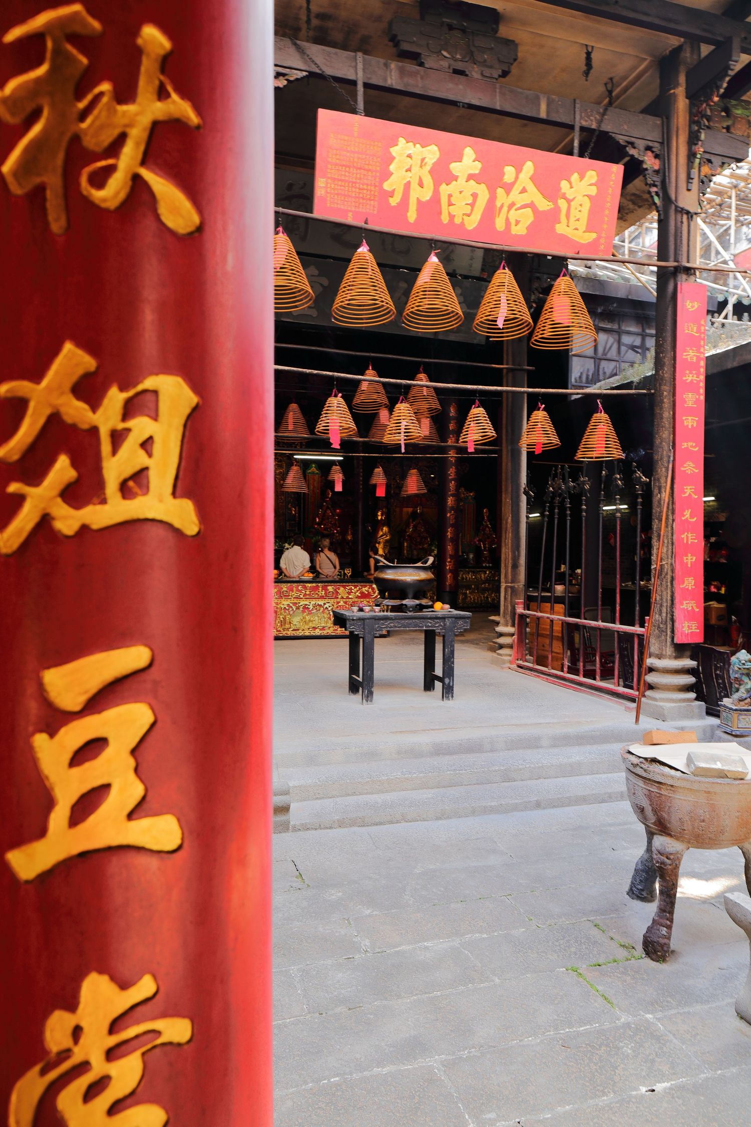 Traditional Chinese temple entrance with red pillars and hanging decorative triangular ornaments.