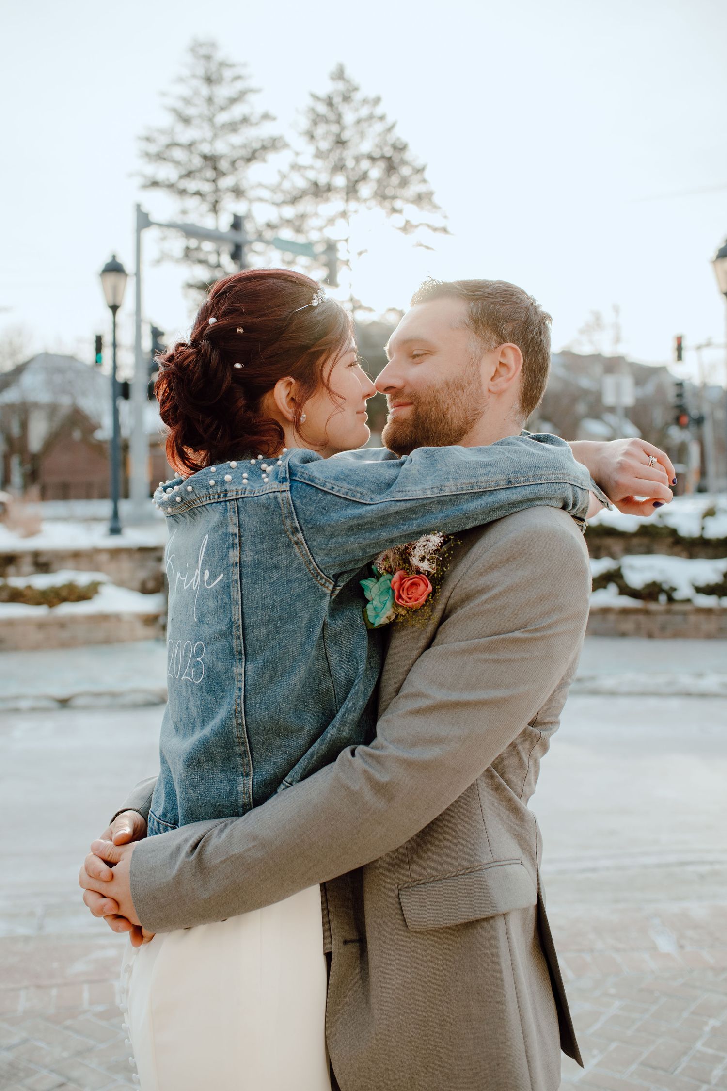 A winter wedding couple embracing outdoors with snow-covered trees in the background.