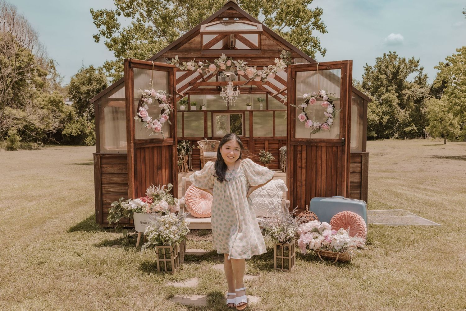 Garden pavilion decorated with pink flowers and vintage-style accessories in natural setting.