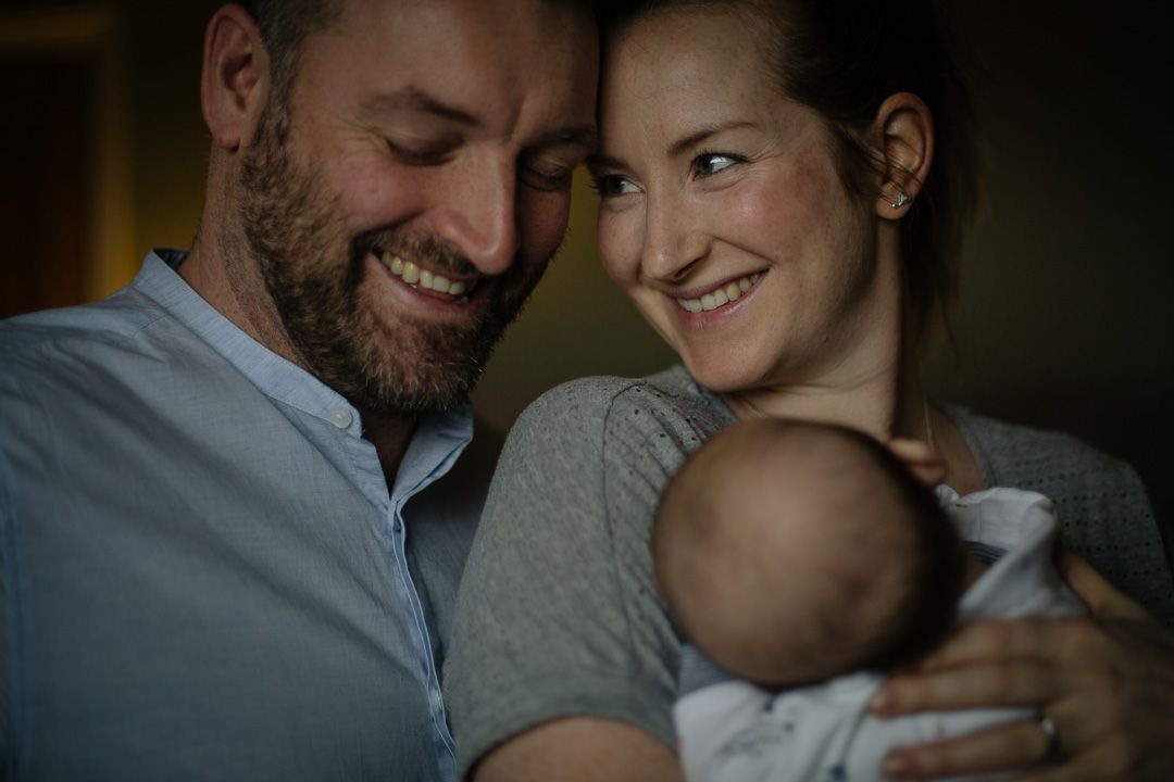 An intimate family moment with a newborn baby in moody lighting.