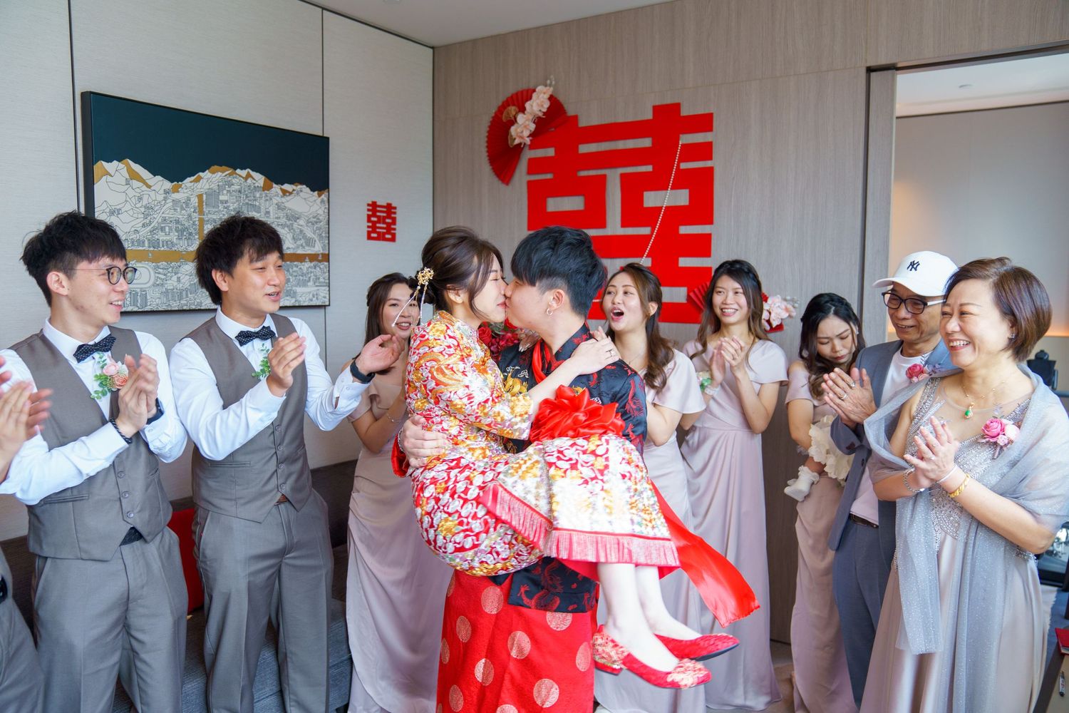 Wedding party celebration with guests in grey attire and red traditional decorations.