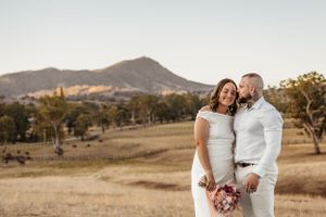 Elegant couple poses against scenic mountain backdrop during golden hour.