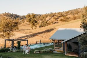Rustic venue with wooden buildings set against rolling countryside hills.