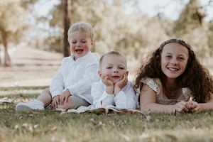 Playful family lying on grass during outdoor photo session.