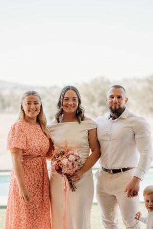 Wedding party in white and peach attire posing for outdoor group photos.