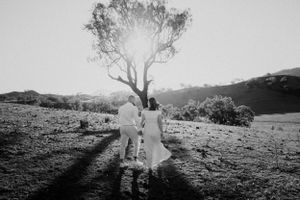 Silhouettes of people against a bright sunset in a rural landscape.