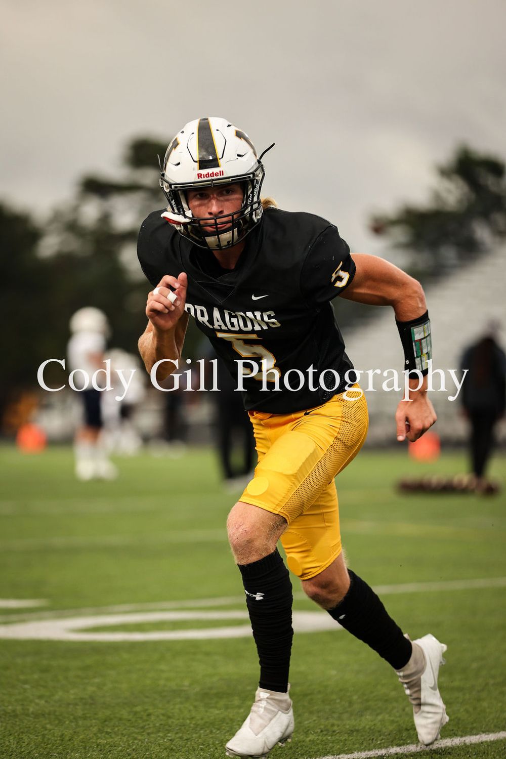 Football player in black jersey and yellow pants runs during practice drill.