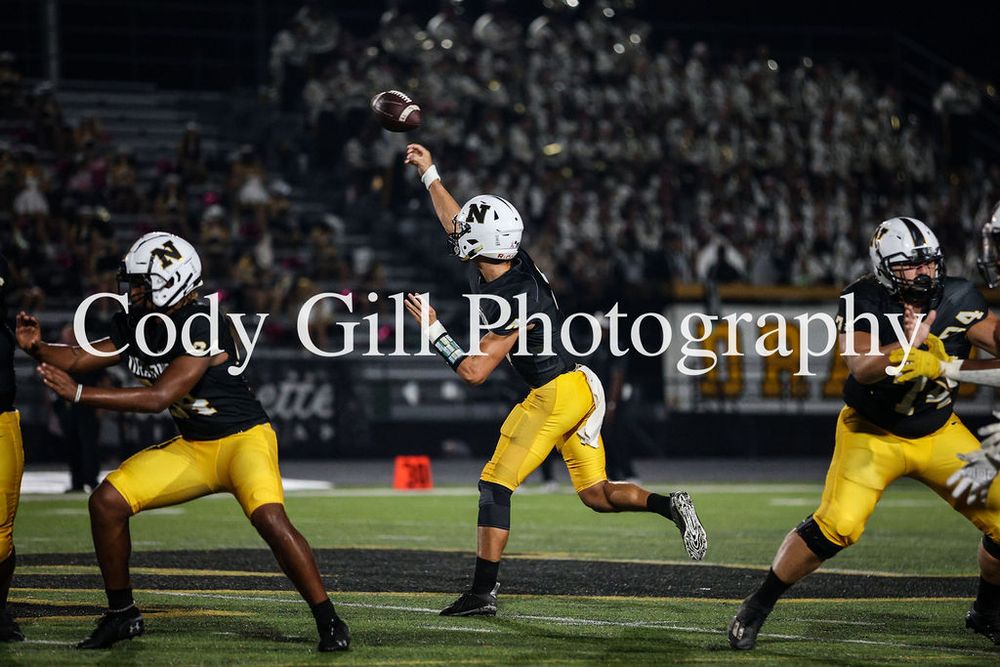 Football player jumps high to make a catch during nighttime game action.