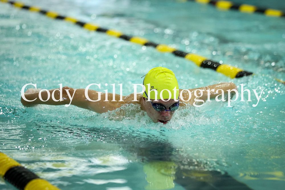 Swimmer performs butterfly stroke in a pool with yellow and black lane markers.