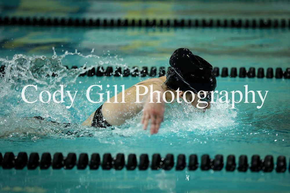 Competitive swimmer performs freestyle stroke in a pool with lane dividers visible.