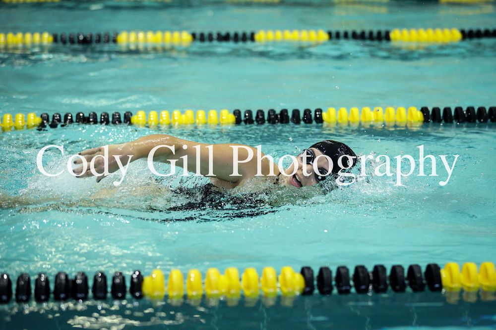 Swimmer glides through pool water with black and yellow lane dividers visible.