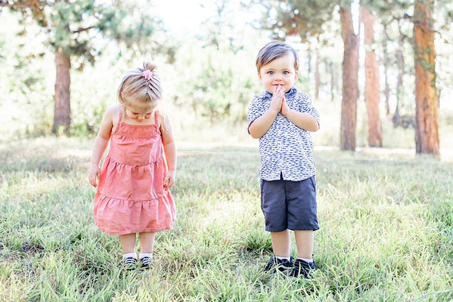Toddler cousins stand in the grass together in Black Forest, Colorado.