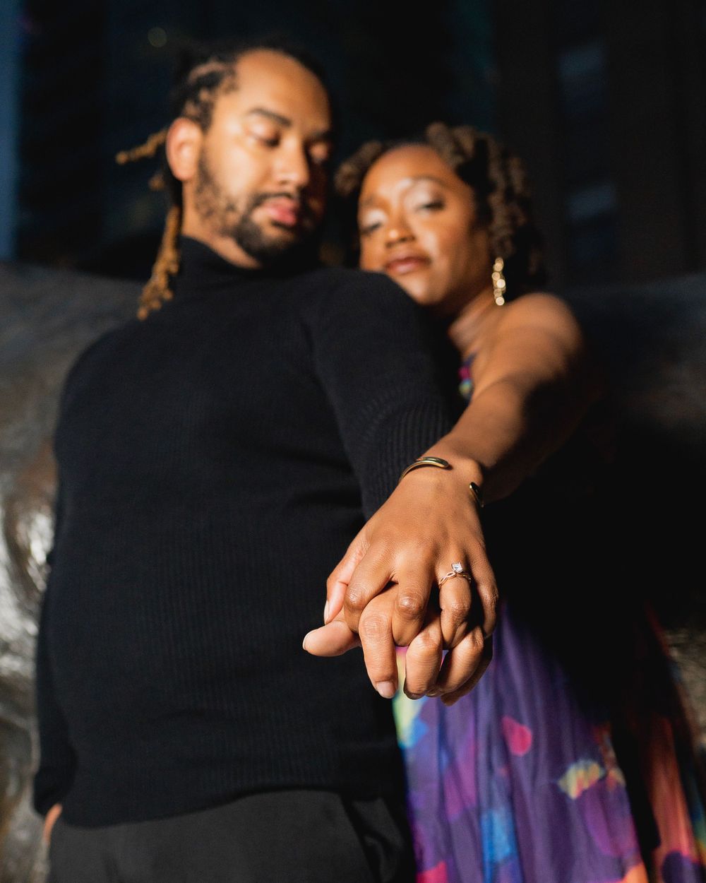 Close-up of couple holding hands showing engagement ring.