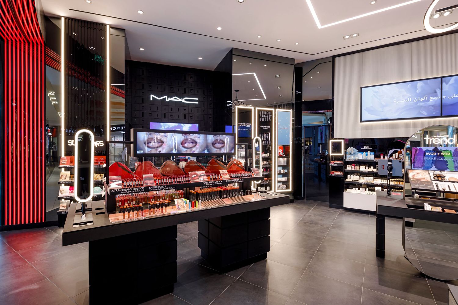 MAC cosmetics retail space with illuminated displays and red accent lighting.