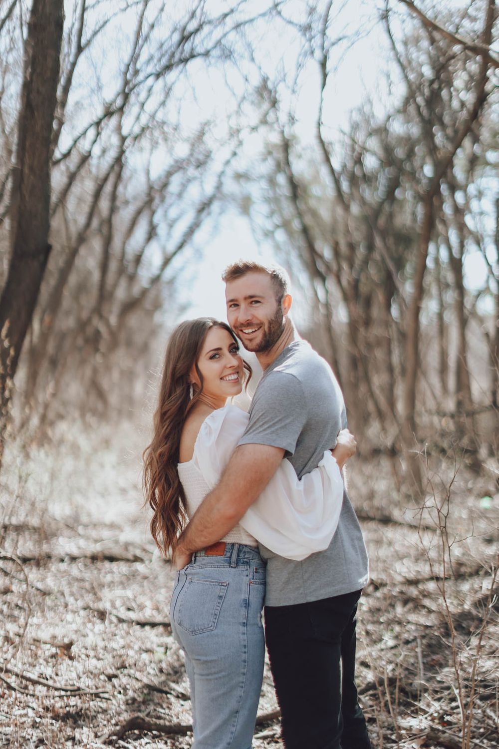 Couple in casual attire sharing joyful moments and laughter during an outdoor photoshoot.
