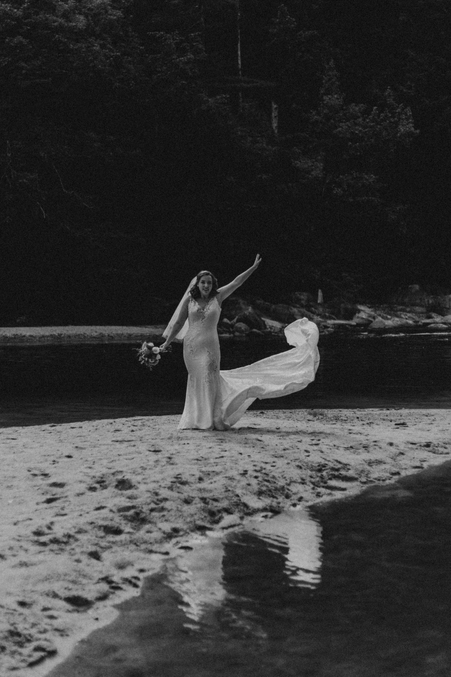 Black and white photo of flowing dress catching wind on beach.