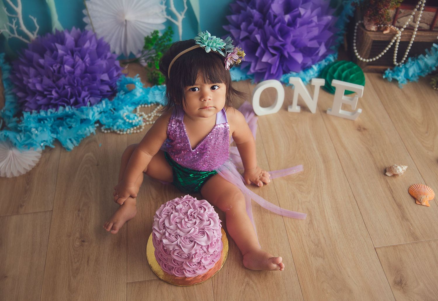 baby girl looking at the camera with pink cake