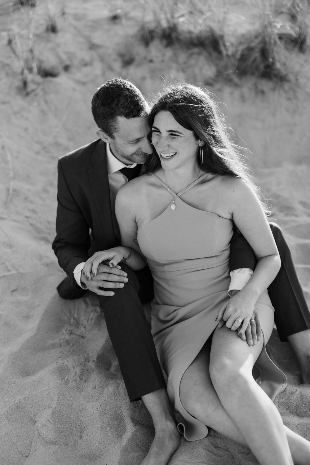 A black and white portrait of a couple sharing an intimate moment on the beach.
