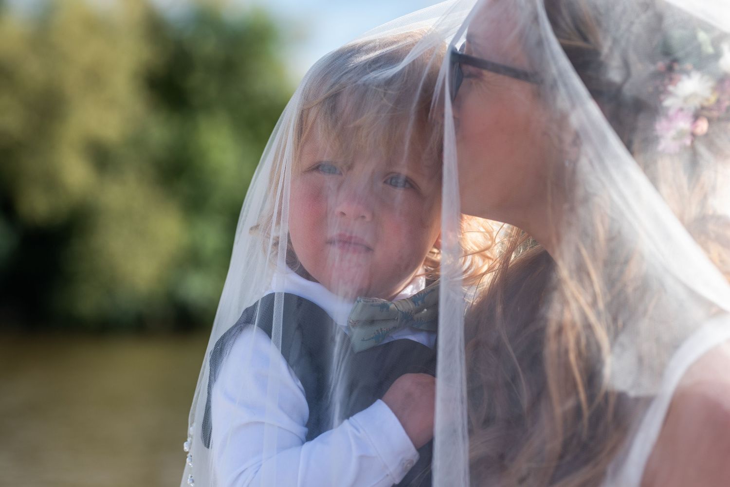 Close-up shot of wedding couple embracing under a delicate veil outdoors.