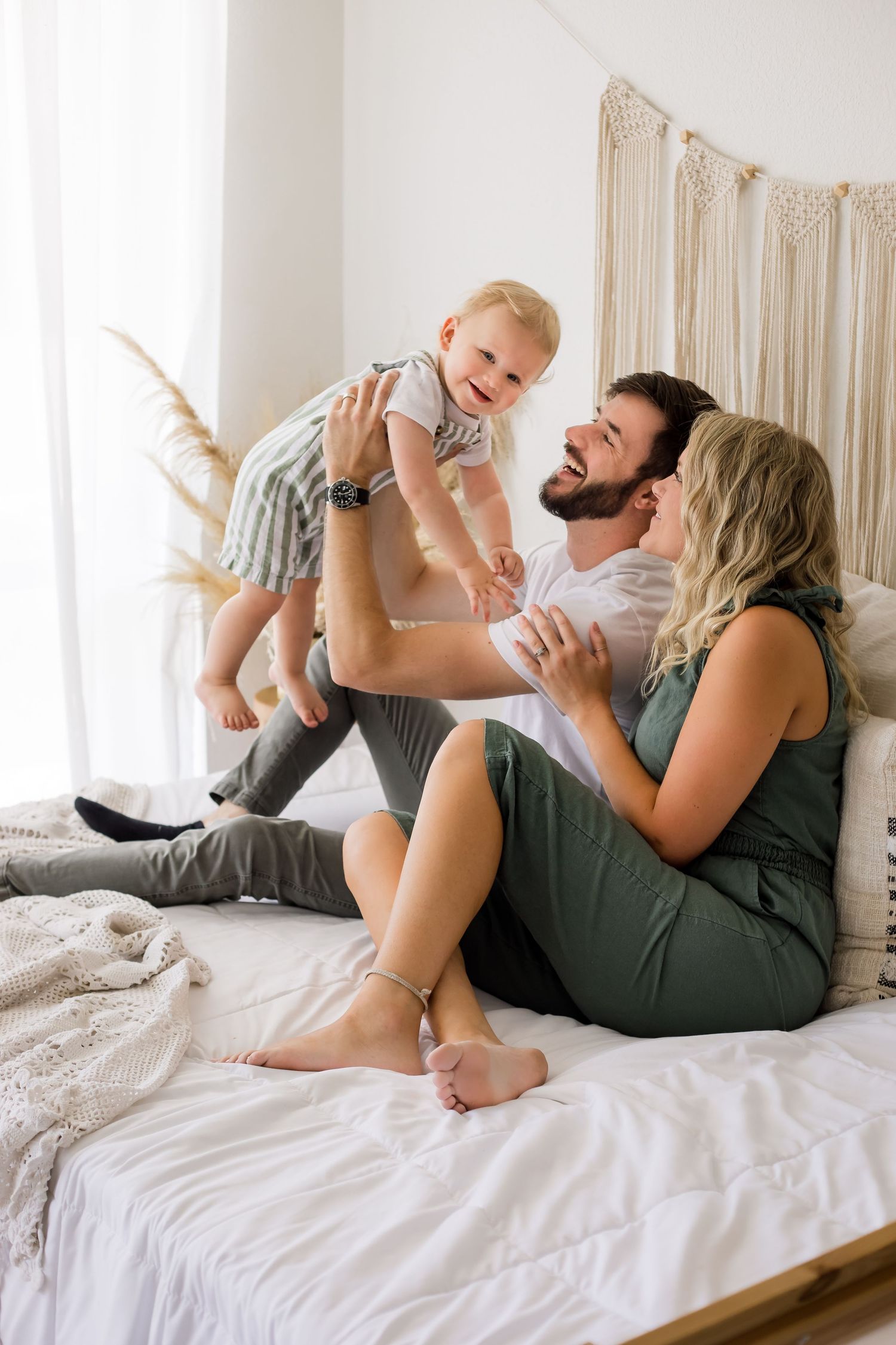 A fun and casual lifestyle portrait of a family playing on the bed with their baby in the studio.
