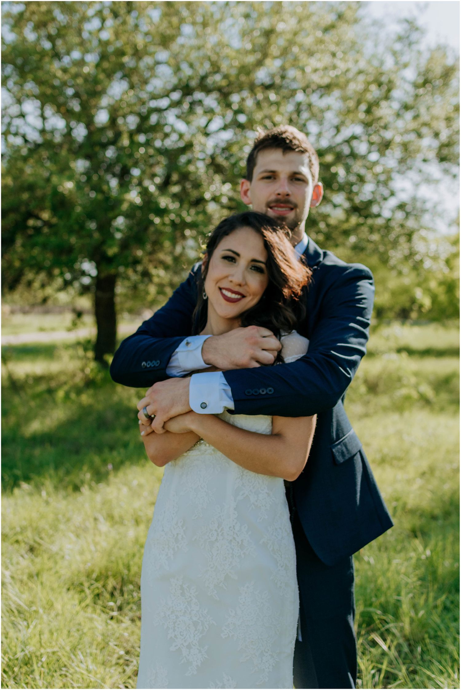A romantic embrace captured in golden sunlight with trees in the background.