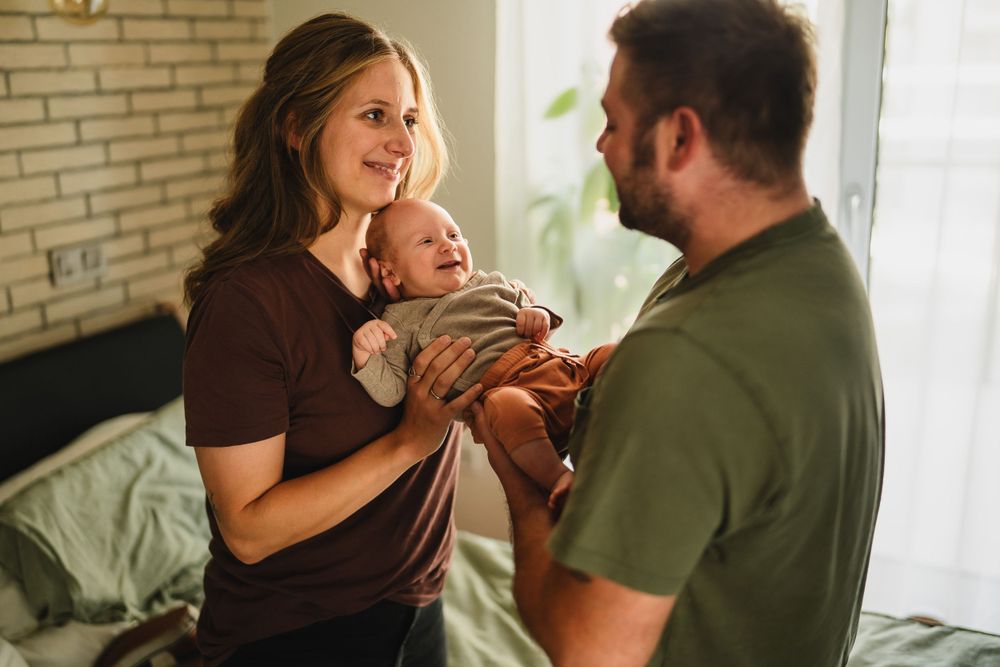 A tender family moment as parents share joyful interaction with their baby in a bedroom.