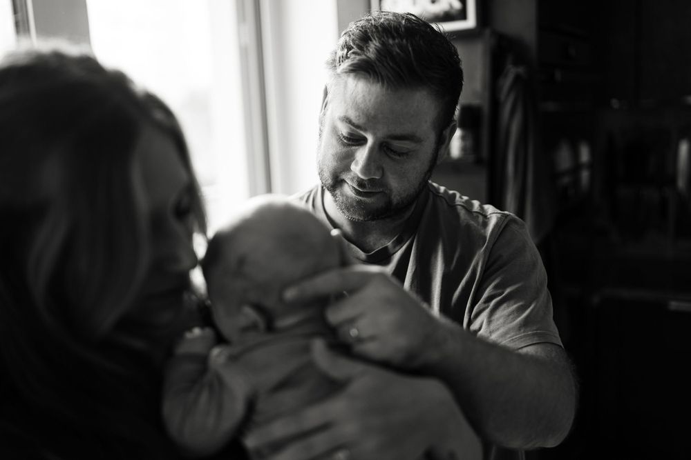 A tender family moment captured in black and white as they hold a small baby.