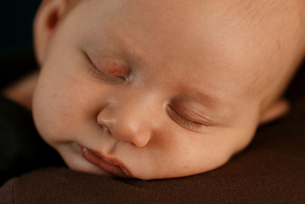 Close-up of peaceful sleeping infant against brown fabric background.