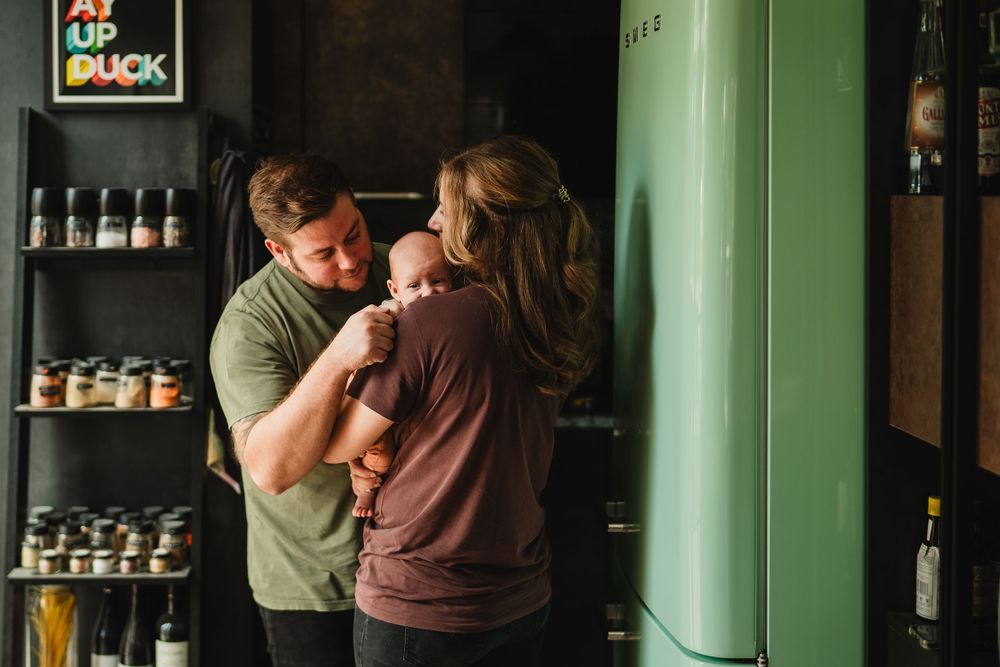 A tender moment shared between two people in a kitchen with a mint green fridge and shelving.