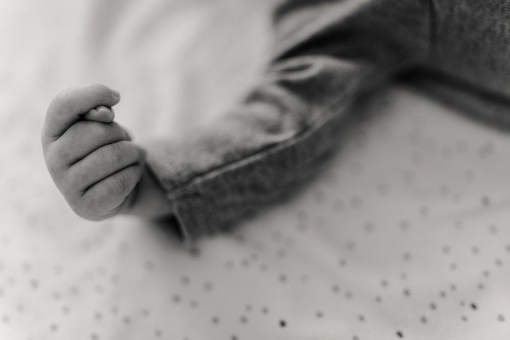 Artistic black and white macro shot of an infant's toes against a spotted fabric.