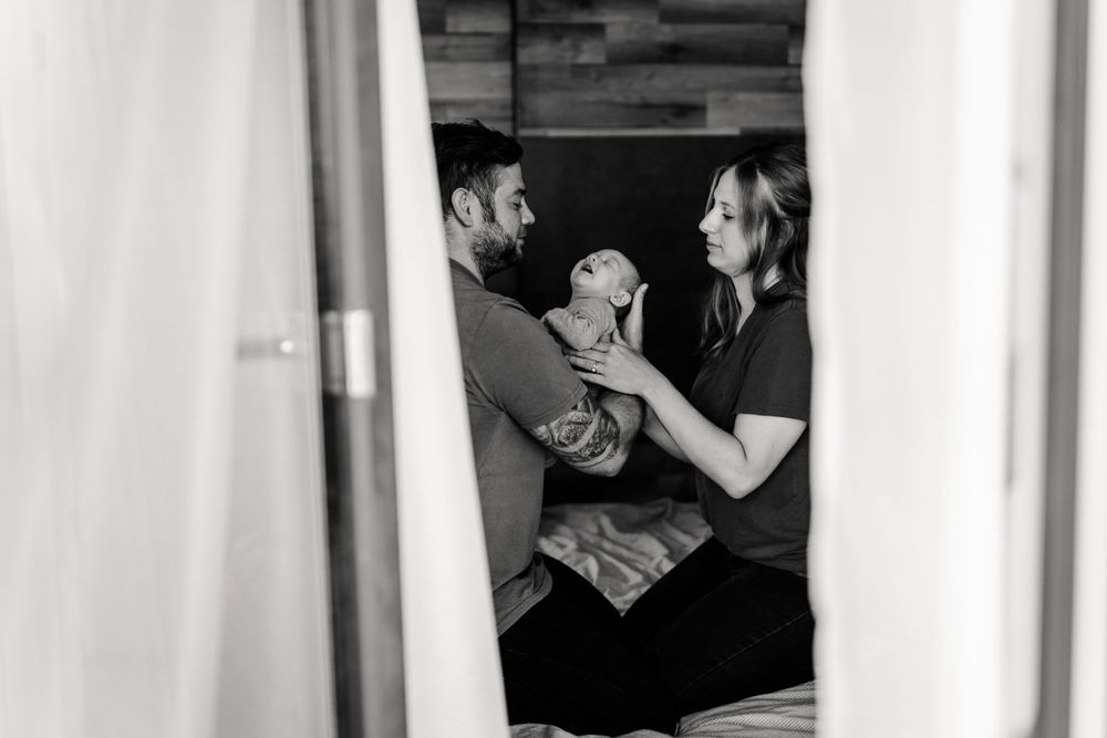 Black and white photo captures an intimate family moment through a doorway.