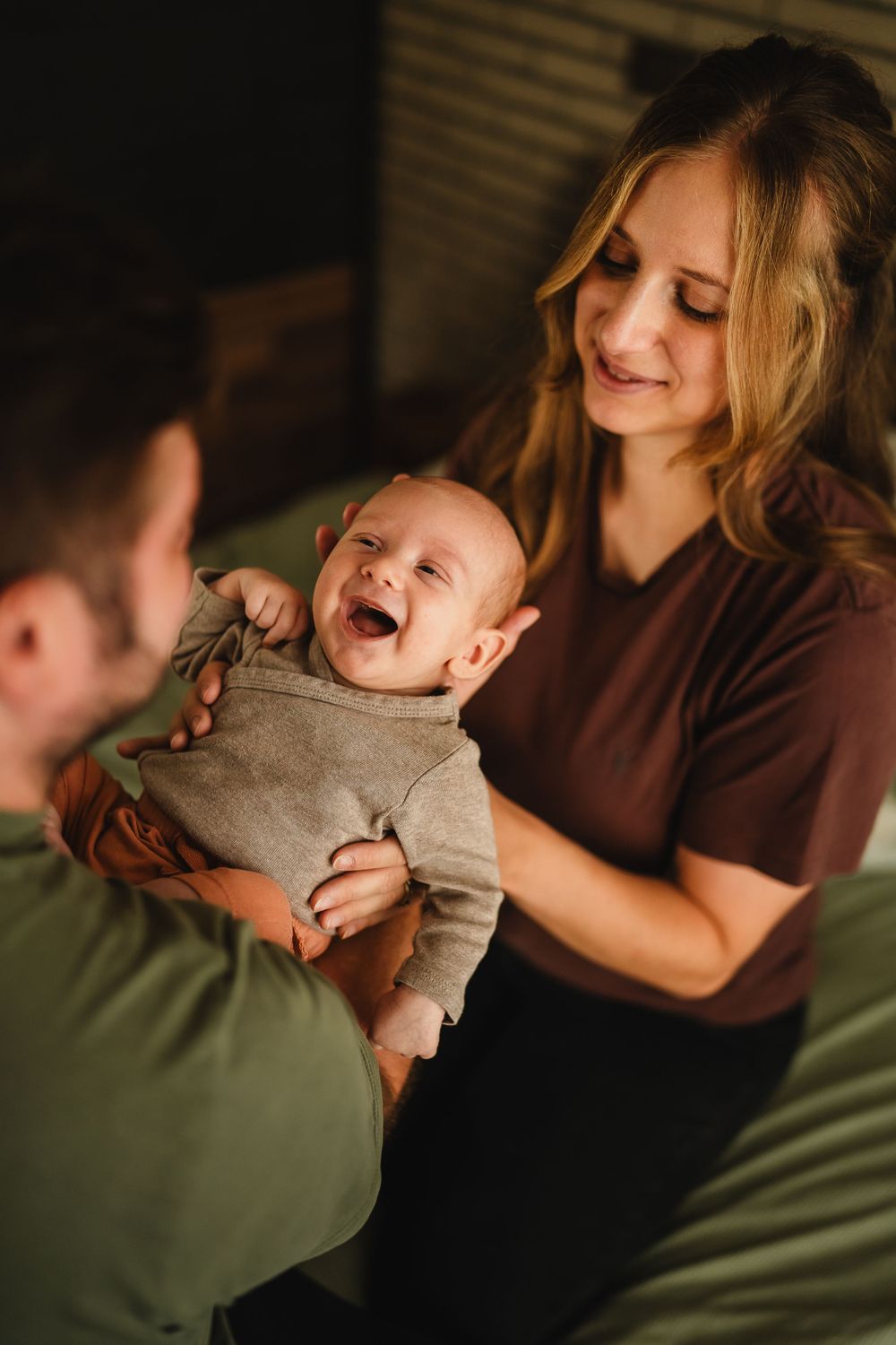 A laughing baby in gray sweater shares a heartwarming moment with family.