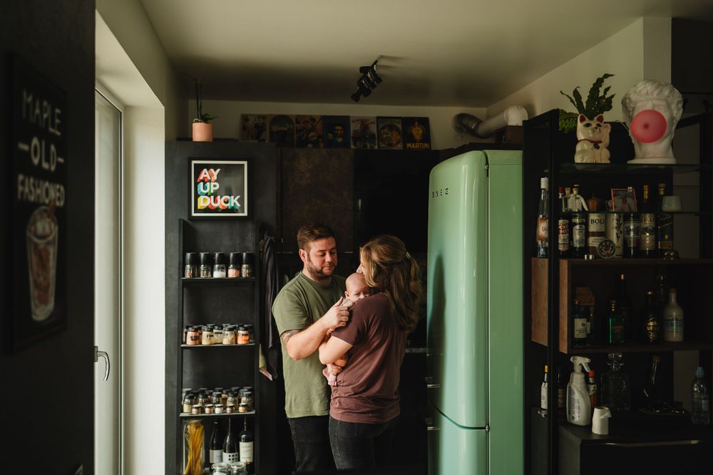 Intimate scene in a kitchen with mint green refrigerator and dark shelving filled with bottles.