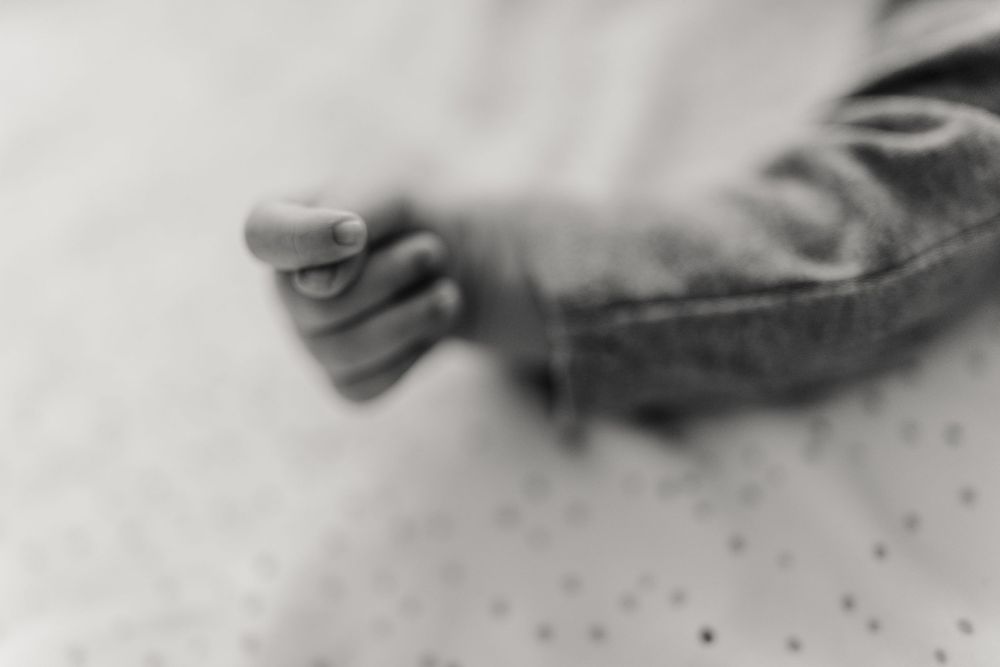 Soft focus black and white photograph of baby feet on dotted textile.